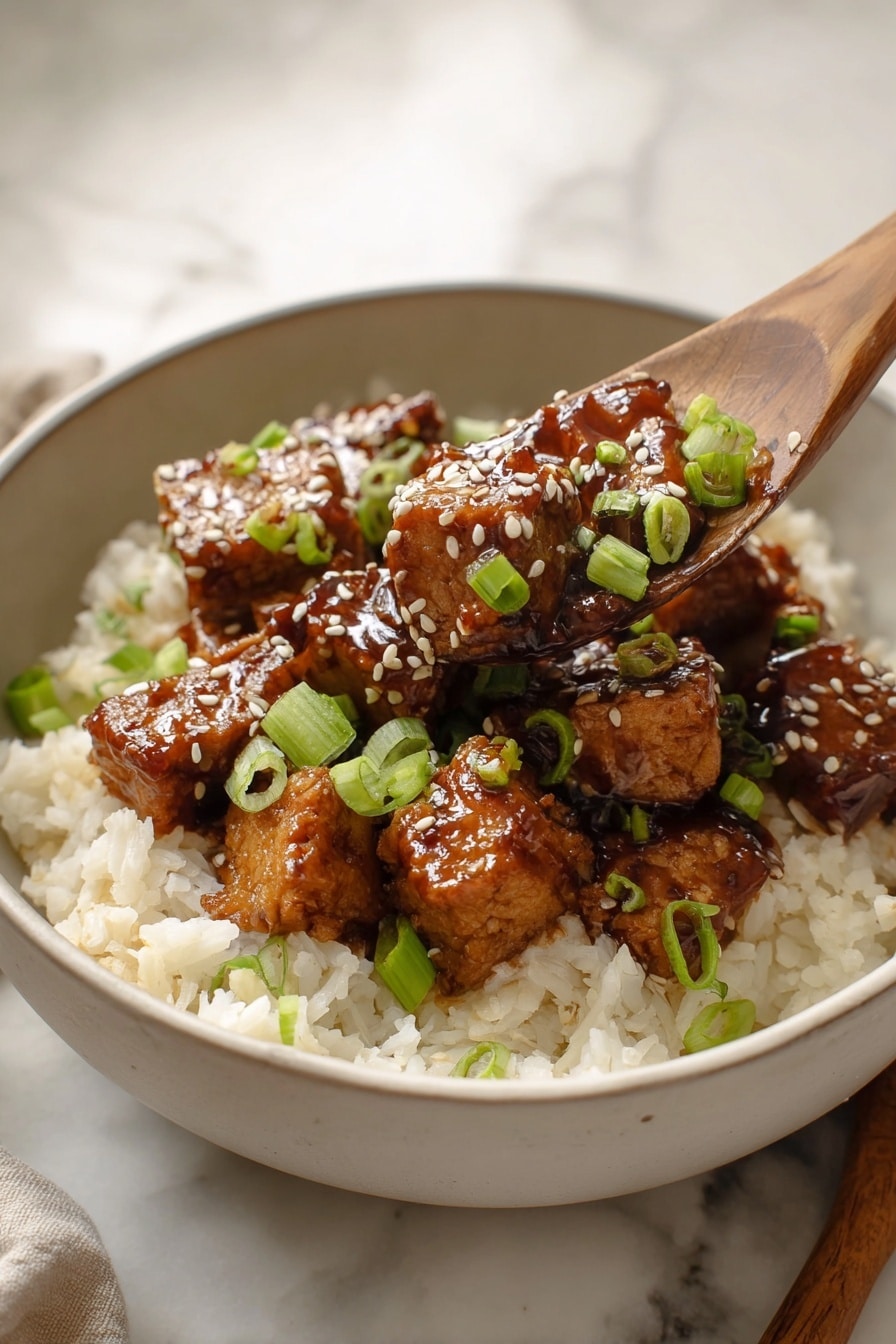 A bowl with a bottom layer of soft white rice, topped with multiple pieces of brown glazed tofu with a shiny texture, sprinkled with white sesame seeds and green sliced scallions. The tofu pieces appear tender, arranged in a small pile in the center of the bowl. The bowl is white and sits on a white marbled surface with a wooden spoon partially visible on the right side. Photo taken with an iphone --ar 2:3 --v 7 - Honey BBQ Chicken Thighs, Honey BBQ Chicken, Chicken and Rice Dinner, Easy BBQ Chicken Recipe, Juicy Chicken with Honey BBQ Sauce