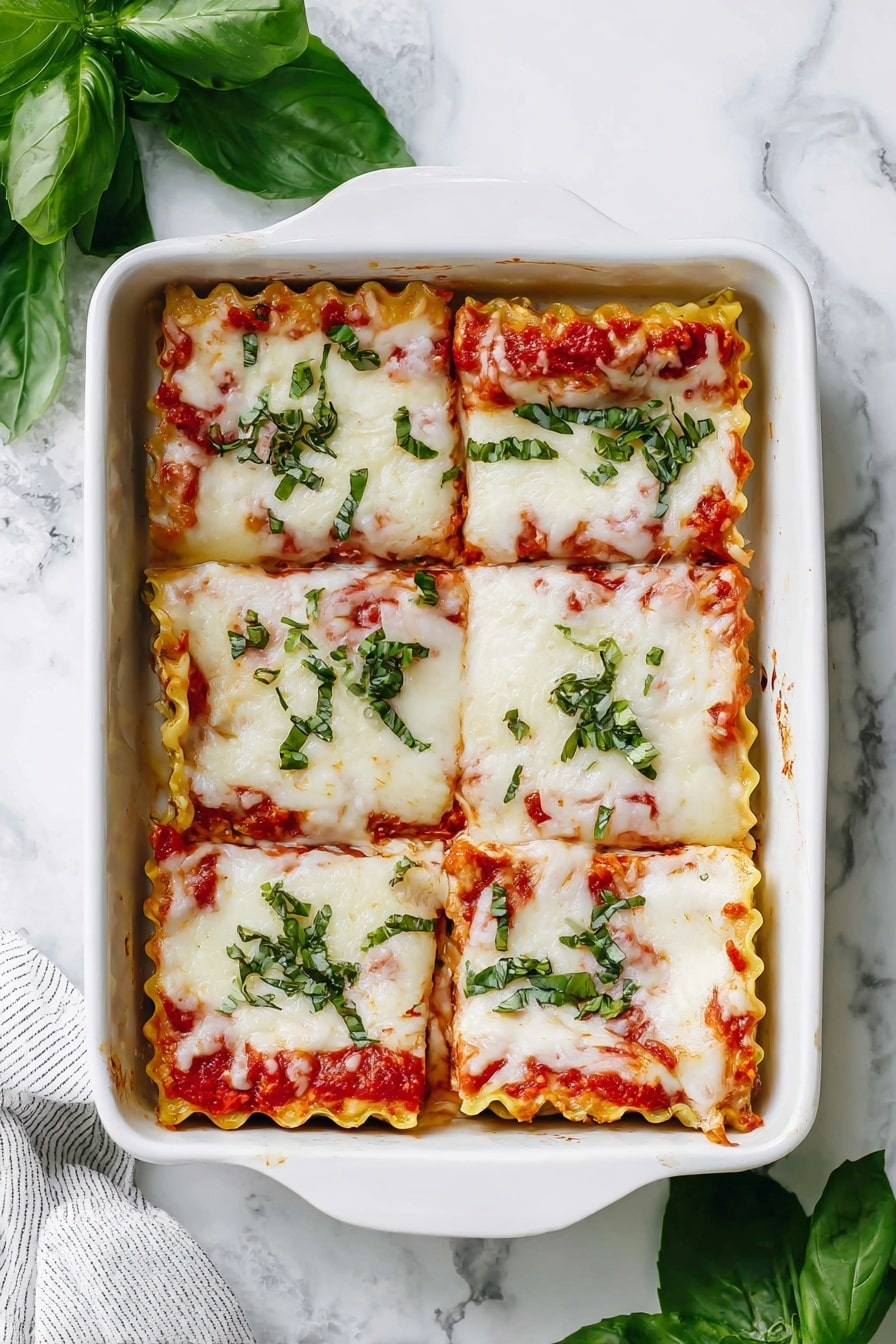 A white baking dish holds six square lasagna pieces arranged in two rows of three. Each piece has a top layer of melted white cheese with a smooth, slightly bubbly texture, streaked with bright red tomato sauce. Fresh green basil leaves and small chopped herbs are sprinkled over the top, adding a vivid contrast. The lasagna edges show ruffled pasta layers beneath the cheese. The dish sits on a surface with a white marbled texture, with some fresh basil leaves placed beside it. Photo taken with an iphone --ar 2:3 --v 7 - Lasagna Roll-Ups with Kale Ricotta and Mozzarella, baked lasagna roll-ups, healthy lasagna roll-ups, easy Italian pasta dishes, vegetarian lasagna roll-ups