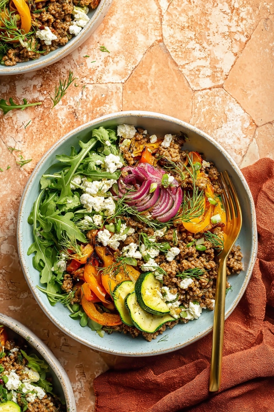 A bowl filled with several layers starting at the bottom with fresh, bright green arugula leaves. The middle layer has cooked ground meat mixed with sautéed vegetables like orange bell peppers, sliced zucchini with green skin and soft yellow inside, and red onions. On top, there are small white cheese crumbles and green sprigs of dill scattered around. The bowl is white with a subtle light blue inside, and a gold fork rests on the right edge inside the bowl. The background is a soft rustic orange tile with a white marbled texture on the table, and a rust-colored cloth is placed to the right. Photo taken with an iphone --ar 2:3 --v 7 - Mediterranean Beef and Veggie Skillet, Mediterranean Beef and Veggie Skillet recipe, healthy beef skillet dinner, quick Mediterranean beef meal, one-pan beef vegetable dish