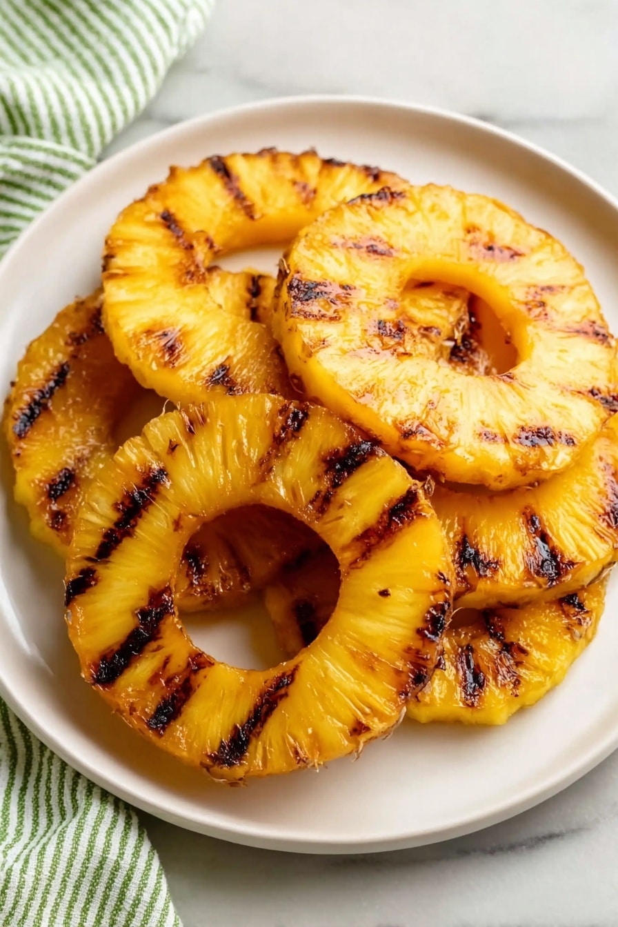 There are six round slices of grilled pineapple on a white plate. The pineapple rings are golden yellow with dark brown grill marks across their surface, giving a slightly caramelized look. The slices overlap each other in a loose pile, showing the juicy, textured fiber of the fruit. The plate is on a white marbled surface with a green and white striped cloth partially visible at the bottom left. The lighting is soft and natural, highlighting the bright and warm colors of the pineapples. photo taken with an iphone --ar 2:3 --v 7 - Grilled Pineapple with Lime and Coconut, tropical grilled pineapple recipe, easy grilled pineapple dessert, citrus coconut fruit grill, quick summer pineapple treat