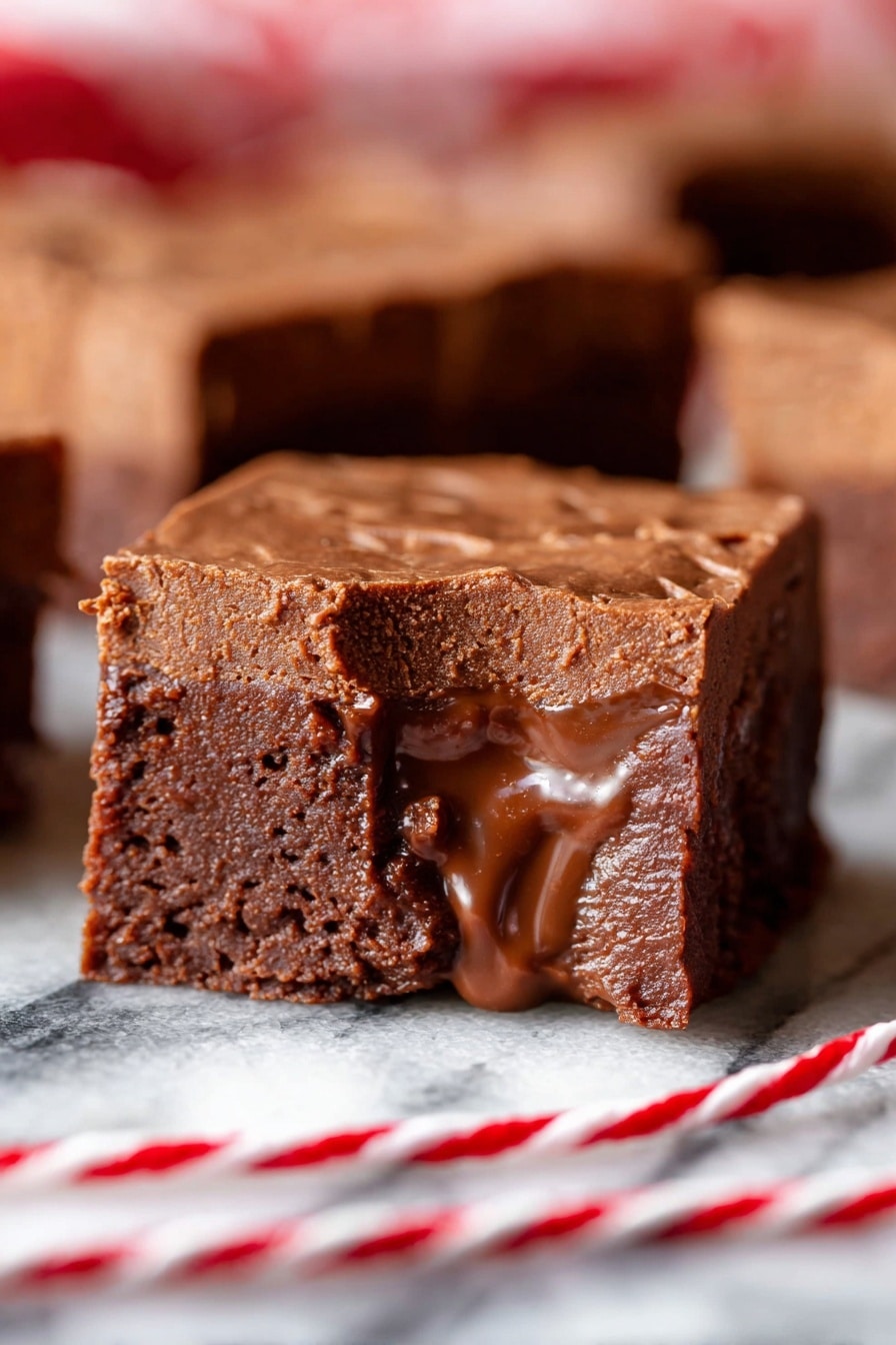 A close-up view of a chocolate fudge square shows two distinct layers: the top layer is thick, dense, and slightly crumbly, with a matte finish and rich brown color; the bottom layer is gooey, shiny, and slightly melted, darker in brown shade, and oozes slightly at the edges. In the background, there are more pieces of the same fudge, all with similar texture and color. The fudge rests on a white marbled surface with a red and white twisted string in front of it. Photo taken with an iphone --ar 2:3 --v 7 - Mom’s Easy Fudge, easy chocolate fudge, homemade fudge recipe, quick fudge recipe, creamy fudge dessert