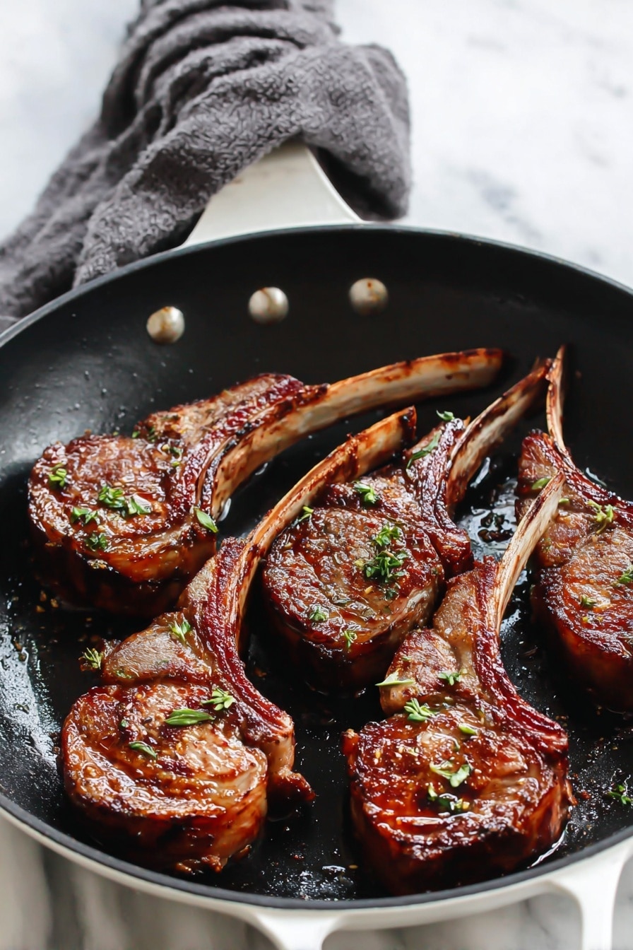 In the image, there are four cooked lamb chops arranged in a black frying pan, their brown, crispy surfaces showing grill marks and a slightly shiny texture from the cooking oil. Each chop has a clear bone handle, lighter in color, extending outward, giving the dish a rustic and rich look. Small bits of green herbs are sprinkled on top, adding a fresh touch of color. The background is a white marbled surface, and the overall scene captures a close-up, warm, and appetizing view of the cooked meat. Photo taken with an iphone --ar 2:3 --v 7 - Garlic Butter Lamb Chops, Lamb Chops Recipes, Easy Lamb Dinner, Quick Lamb Recipes, Flavorful Lamb Chops